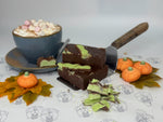 Chocolate dessert with green toppings on a table with pumpkins and leaves.