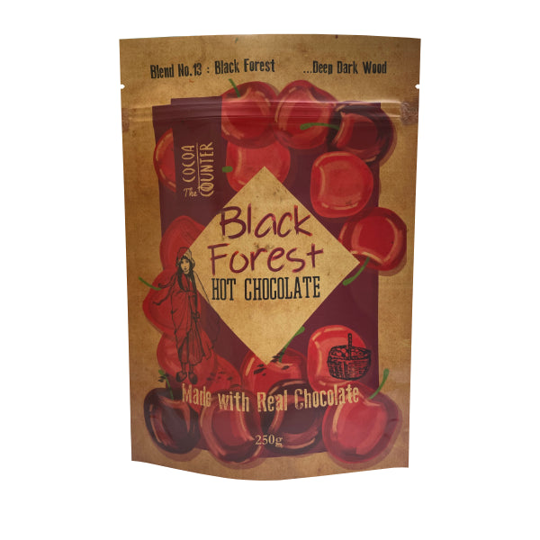 Packaging of Black Forest hot chocolate with cherries and a woman in a hood on a white background.