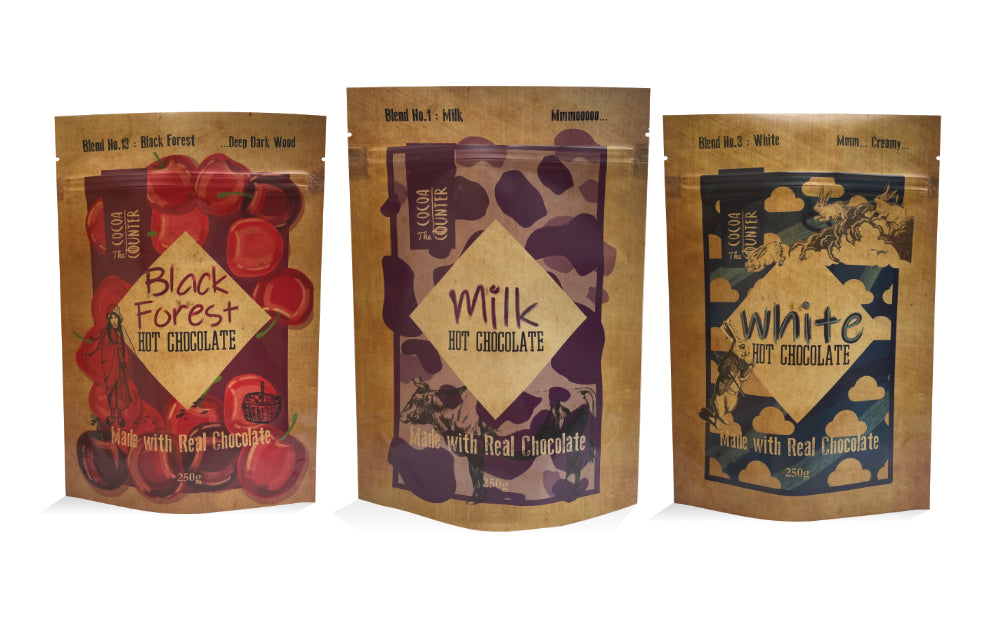 Three packages of hot chocolate with different flavors on a white background